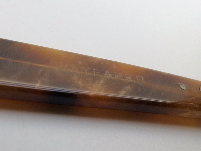 May include: Close-up of a Wayfarer style eyeglass frame in a tortoiseshell pattern. The frame is a warm brown color with a slight gradient. The word "WAYFARER" is etched into the frame.