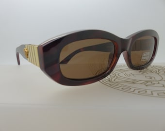 May include: Brown tortoiseshell sunglasses with a gold accent on the temples. The sunglasses have a rectangular shape with brown tinted lenses. The brand name is visible on the right lens.