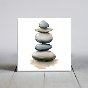 May include: Watercolor painting of a stack of smooth, gray stones. The stones are balanced on top of each other against a white background. The artwork has a minimalist and zen-like aesthetic, with soft shadows and muted colors.