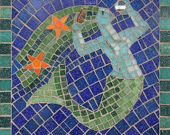 Glass mosaic wall panel showing a Mermaid combing her hair and looking in a mirror