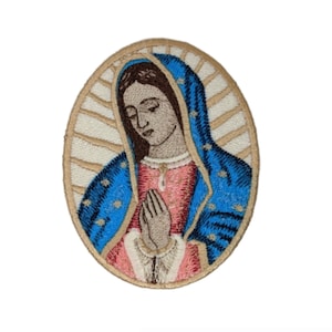 May include: Embroidered patch depicting the Virgin Mary in a blue robe with a gold halo. She is praying with her hands clasped together. The patch is oval-shaped and has a beige background.