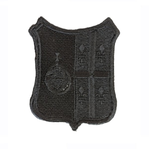 May include: Black embroidered patch in the shape of a shield with a fleur-de-lis design.