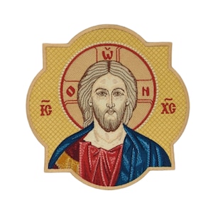 Puede incluir: Icono religioso bordado que representa a Jesucristo. La imagen muestra a Jesús con cabello castaño claro y barba, vistiendo una túnica azul y una prenda roja. El icono está sobre un fondo dorado con letras griegas.