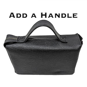 Può includere: Borsa a zip in pelle nera con manico superiore. Il testo "ADD A HANDLE" è stampato sopra la borsa.