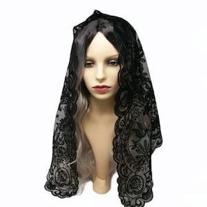 May include: Black lace mantilla with a delicate floral pattern. The mantilla is draped over a mannequin's head and shoulders.