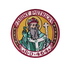 Puede incluir: Parche bordado circular que representa a San Patricio, con aureola, báculo y trébol. El diseño incluye el texto "SAINT PATRICKS" y "A.D. 464" dentro de un borde decorativo con acentos de estrellas.
