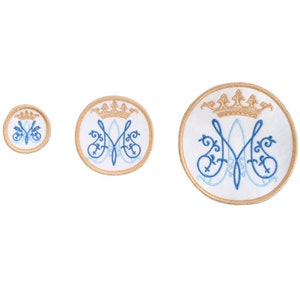 May include: Three embroidered patches with a blue and white image of the Virgin Mary's monogram, a crown, and a gold outline. The patches are circular and come in three sizes.