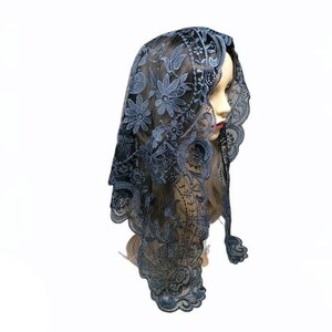 Puede incluir: Una mantilla de encaje negro con un patr&oacute;n floral. El encaje es delicado y tiene un brillo sutil. La mantilla es un tocado tradicional que usan las mujeres en algunas culturas.