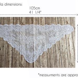 May include: White lace mantilla with a scalloped edge. The mantilla measures 41 1/4 inches by 22 3/4 inches. *Measurements are approximate*