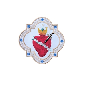 May include: Embroidered patch with a gold frame and a white background. The center of the patch features a red heart with a gold crown, a white floral wreath, and a silver dagger piercing the heart.