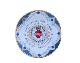 May include: A white circular patch with a blue border and a gold embroidered image of the Immaculate Heart of Mary. The text around the image reads "COR MARIAE IMMACULATUM REFUGIUM PECCATORUM".