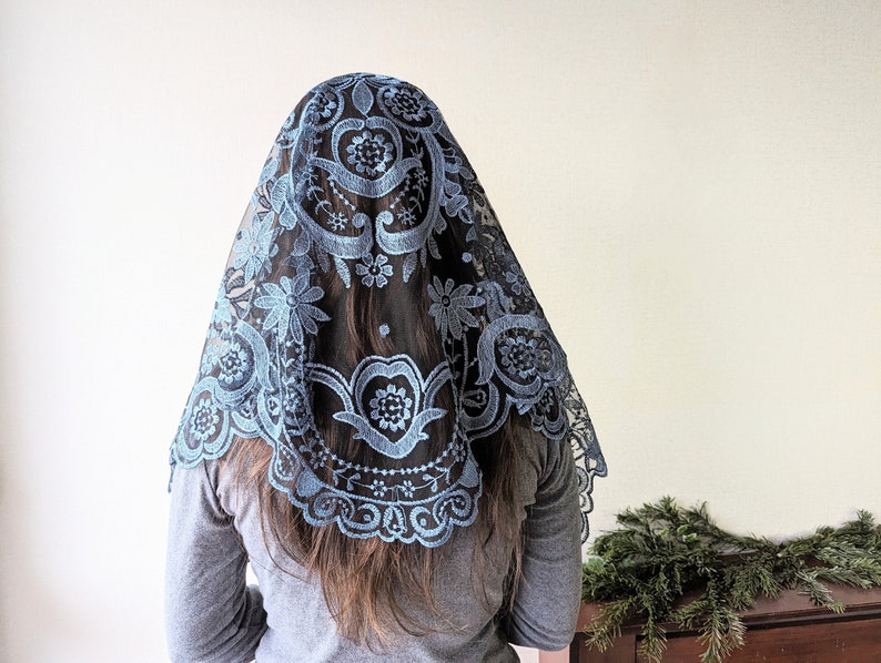 Puede incluir: Una mantilla de encaje azul con bordados florales. El encaje es delicado e intrincado, y el bordado es de un hermoso tono azul.