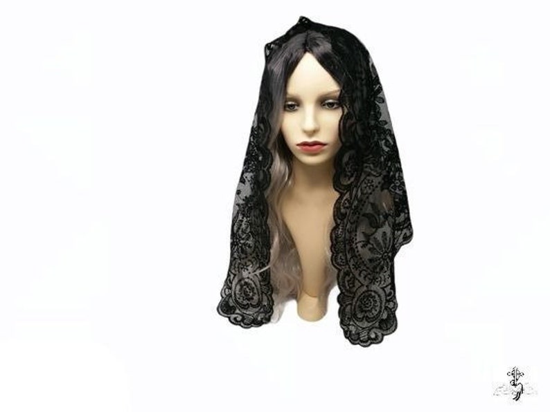 May include: Black lace mantilla with a delicate floral pattern. The mantilla is draped over a mannequin's head and shoulders.