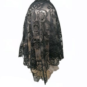 May include: Black lace veil with a floral pattern. The veil is made of delicate, sheer fabric and has a scalloped edge.