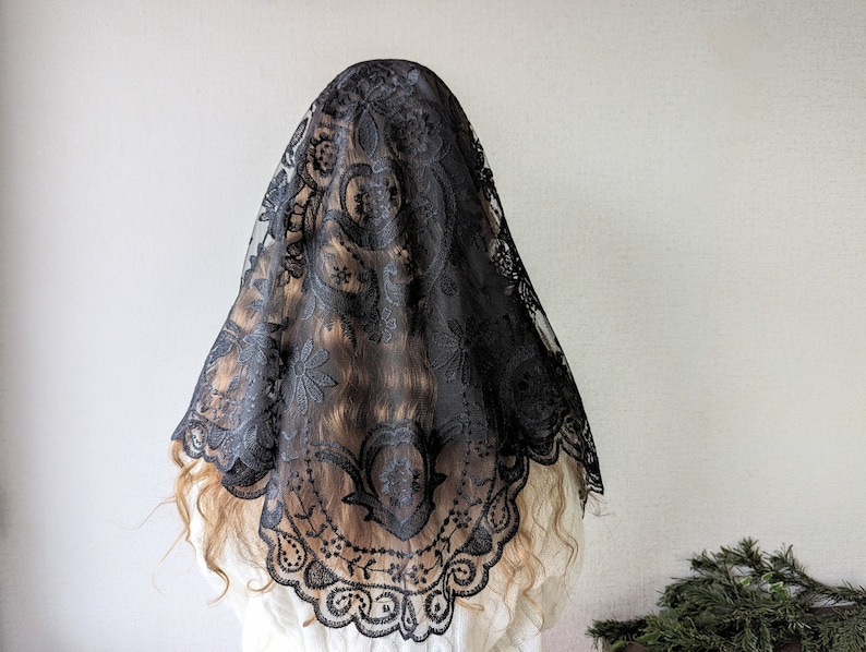 May include: Black lace mantilla with a floral pattern. The lace is delicate and intricate.