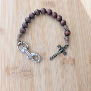 May include: A brown wooden rosary with a silver clasp and a metal crucifix.