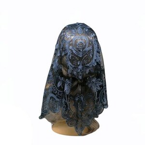 Puede incluir: Una mantilla de encaje azul con un patr&oacute;n floral. La mantilla est&aacute; drapeada sobre la cabeza de un maniqu&iacute;.