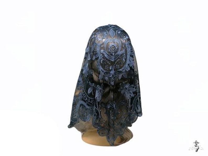 Puede incluir: Una mantilla de encaje azul con un patr&oacute;n floral. La mantilla est&aacute; drapeada sobre la cabeza de un maniqu&iacute;.