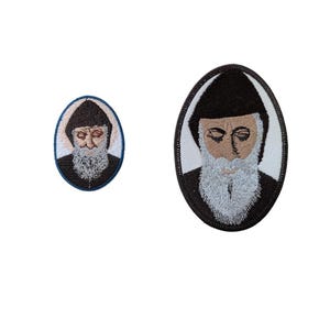 May include: Two embroidered patches featuring a portrait of a man with a beard and a black hooded robe. The larger patch is oval shaped and the smaller patch is round.