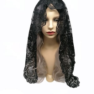 May include: Black lace mantilla with a floral pattern. The mantilla is draped over a mannequin's head.