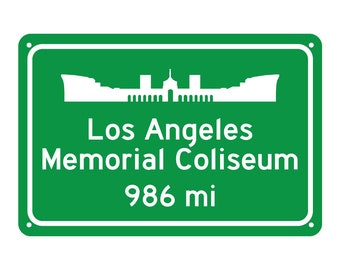 May include: Green road sign with a white silhouette of the Los Angeles Memorial Coliseum and the text "Los Angeles Memorial Coliseum 986 mi".