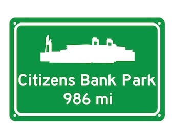 May include: Green road sign with white text and a silhouette of a stadium. The sign reads "Citizens Bank Park 986 mi".