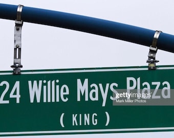 May include: A green street sign with white lettering that reads "24 Willie Mays Plaza (KING)".