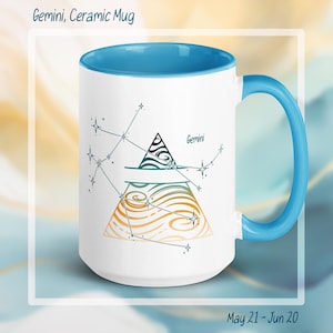 May include: White ceramic mug with a blue interior and handle. The mug features a Gemini constellation design with a triangle and wavy lines in green, orange, and black. Text on the mug reads "Gemini" and "May 21 - Jun 20".