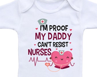 May include: White baby onesie with a pink heart wearing a nurse's hat and holding a stethoscope. The onesie has the text "I'm proof my daddy can't resist nurses" with a pink heart and a heartbeat graphic.