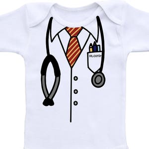 Op de afbeelding: Witte baby romper met een geprint dokterskostuum. Het kostuum bevat een witte jas, een rood-gele gestreepte das, een stethoscoop en een zakje met potloden en de tekst "DR. CUTIE".