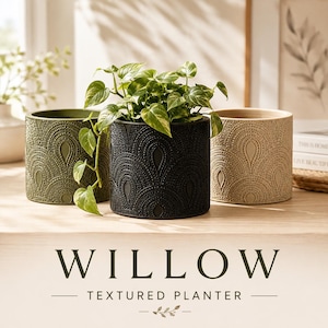 May include: Three cylindrical planters in olive green, black, and beige, each featuring a raised, repeating teardrop and dot pattern. A green leafy plant sits inside the black planter. The text WILLOW TEXTURED PLANTER is displayed below.
