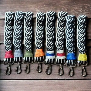 May include: Eight black and white braided straps with colorful accents. Each strap has a silver hook.