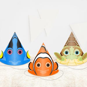 Puede incluir: Tres gorros de fiesta cónicos con diseños de peces y tortugas de dibujos animados. El gorro azul parece un pez cirujano, el naranja un pez payaso y el verde una tortuga marina. Cada gorro incluye una cinta elástica. Texto: LMEPRINTABLES.Etsy.com.