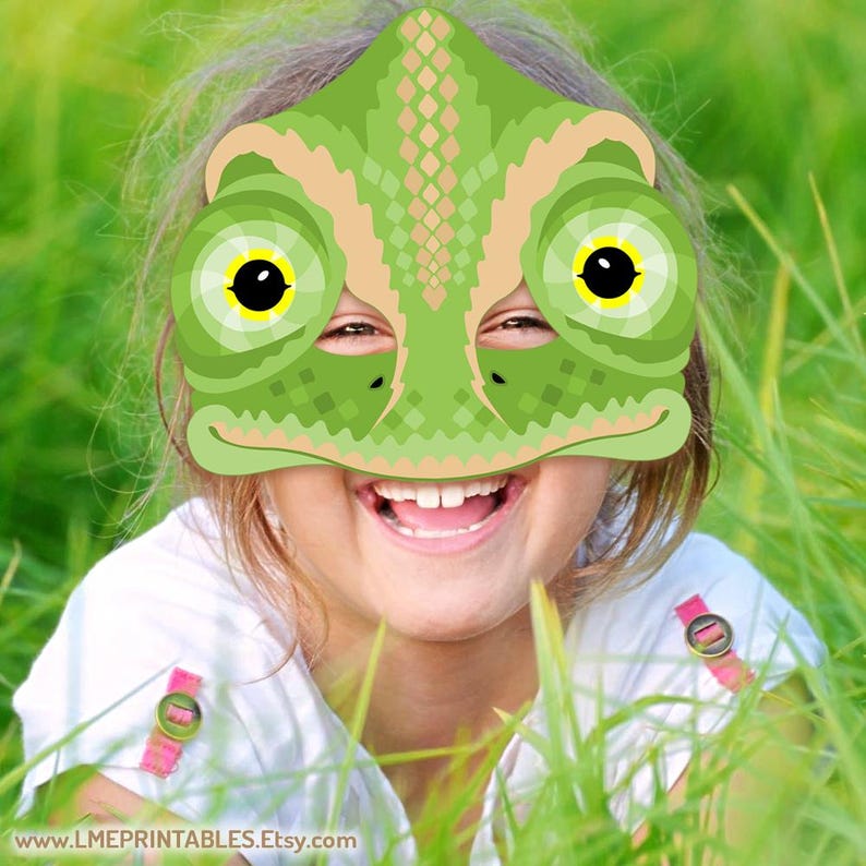Op de afbeelding: Een groen kameleonmasker met gele ogen. Het masker wordt gedragen door een kind dat lacht en naar de camera kijkt.