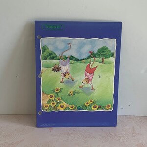May include: A blue binder with a colorful illustration of two cartoon mice doing handstands in a field of sunflowers. The binder has a green label at the top that says "Trapper". The bottom of the binder has text that says "© 1996 The Mead Corporation."