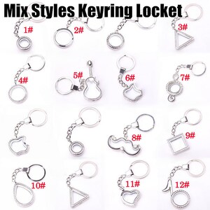 May include: Twelve silver keychains with different charms, including a circle, guitar, cat, music note, mustache, and triangle. Each keychain has a small clear glass locket with rhinestones around the edge.