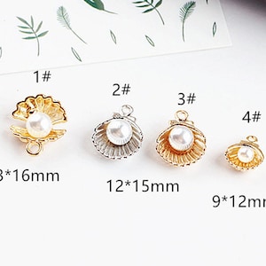 Puede incluir: Cuatro abalorios de concha de color dorado con detalles de perla. Los abalorios son de diferentes tamaños, el más grande mide 13 mm por 16 mm y el más pequeño 9 mm por 12 mm.