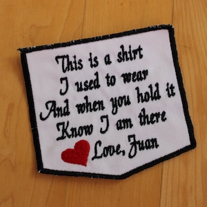 May include: White embroidered patch with black stitching and a red heart. The patch reads "This is a shirt I used to wear And when you hold it Know I am there Love, Juan".