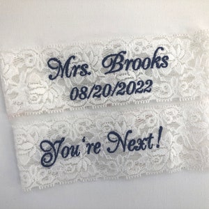 a set of 2 white lace garters for the bride. 
 One garter embroidered with Mrs and her new last name, the other embroidered with "You're Next!"