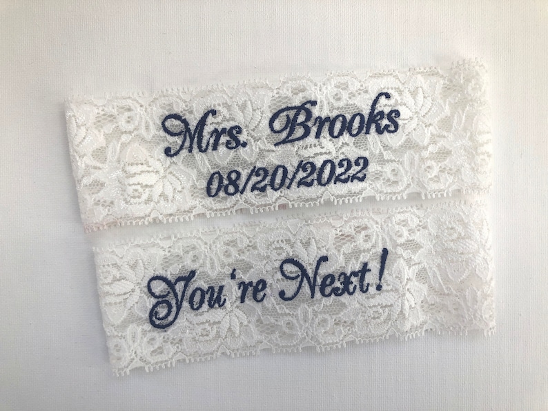 a set of 2 white lace garters for the bride. 
 One garter embroidered with Mrs and her new last name, the other embroidered with "You're Next!"