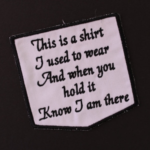 May include: White fabric patch with black embroidered text that reads "This is a shirt I used to wear And when you hold it Know I am there".