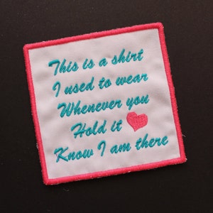 May include: A white embroidered patch with pink stitching around the edges. The text on the patch reads "This is a shirt I used to wear Whenever you Hold it Know I am there". A pink heart is embroidered in the center of the patch.