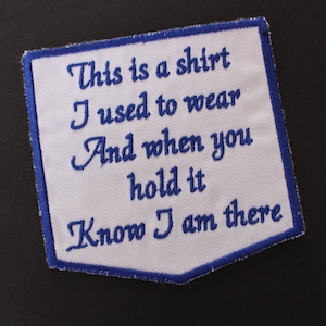 May include: White fabric patch with blue embroidered text that reads "This is a shirt I used to wear And when you hold it Know I am there".