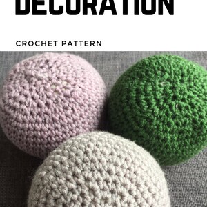 May include: Three crocheted spheres in shades of lavender, green, and gray. The image has the text "INTERIOR DECORATION" and "CROCHET PATTERN" at the top. The spheres are arranged closely together, showcasing the texture of the crochet.