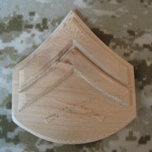 以下が含まれることがあります： 木製の薄い茶色の軍隊の階級章で、表面に2つの山形の記章が彫られています