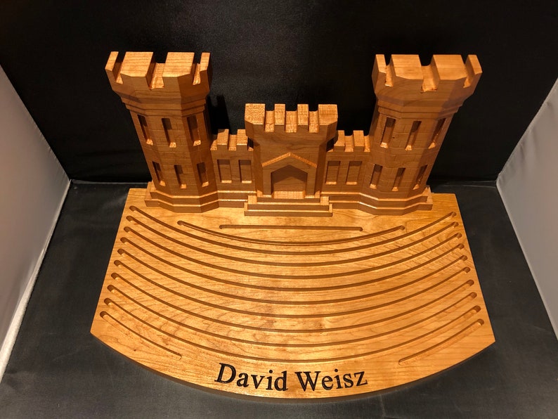 Puede incluir: Un modelo de madera del Pent&aacute;gono con una base curva que tiene ranuras para guardar objetos. La base est&aacute; grabada con el nombre "David Weisz".