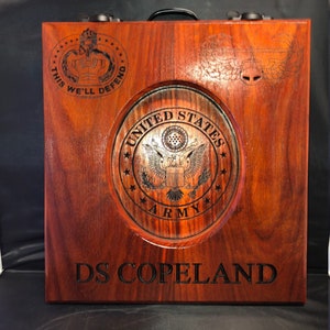 May include: A wooden box with a United States Army seal, the text "This We'll Defend" and "DS Copeland" engraved on it.