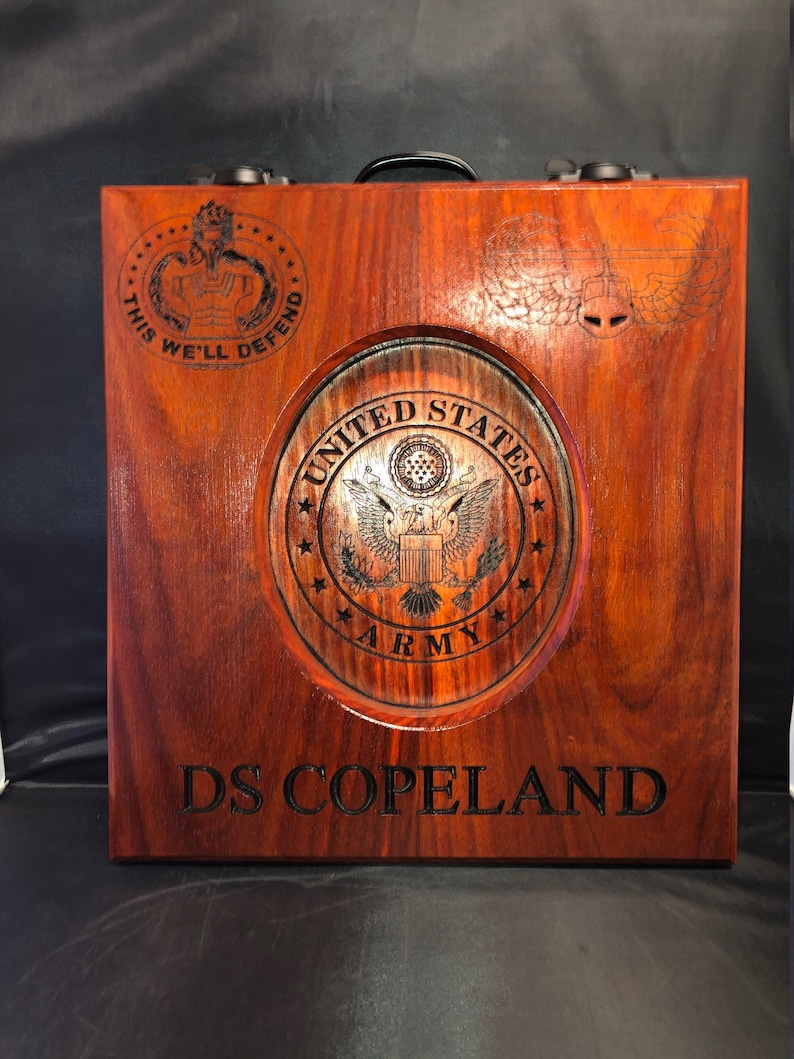 May include: A wooden box with a United States Army seal, the text "This We'll Defend" and "DS Copeland" engraved on it.