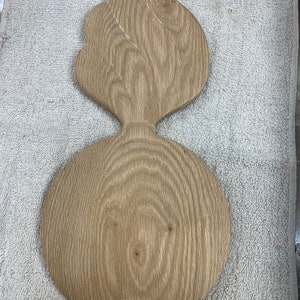 May include: A wooden ornament shaped like a grenade with a flame on top. The ornament is made of light brown wood and has a natural wood finish.
