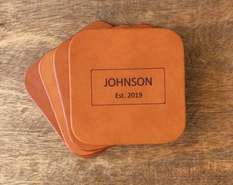 May include: Set of four brown leather coasters with the text "JOHNSON Est. 2019" engraved on the top.